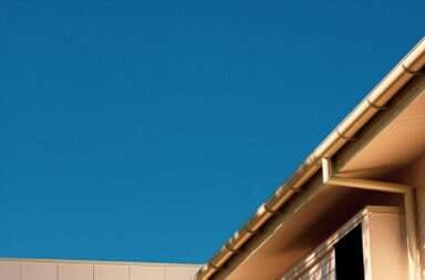 brown concrete building with a roof gutter under blue sky during daytime